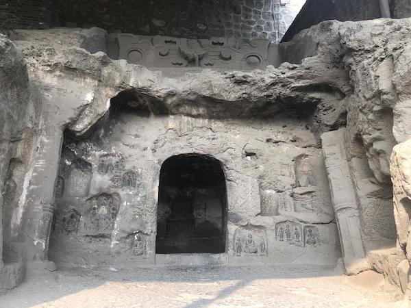 Photo depicting the carved and decorated entrance of a cave in the side of a rock face at the Northern Xiangtangshan Grottoes