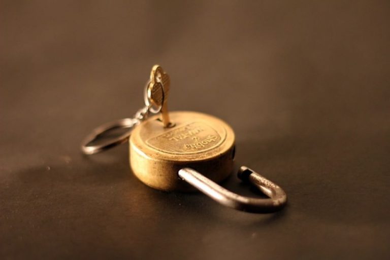 Gold padlock lying open face down with a key in the back